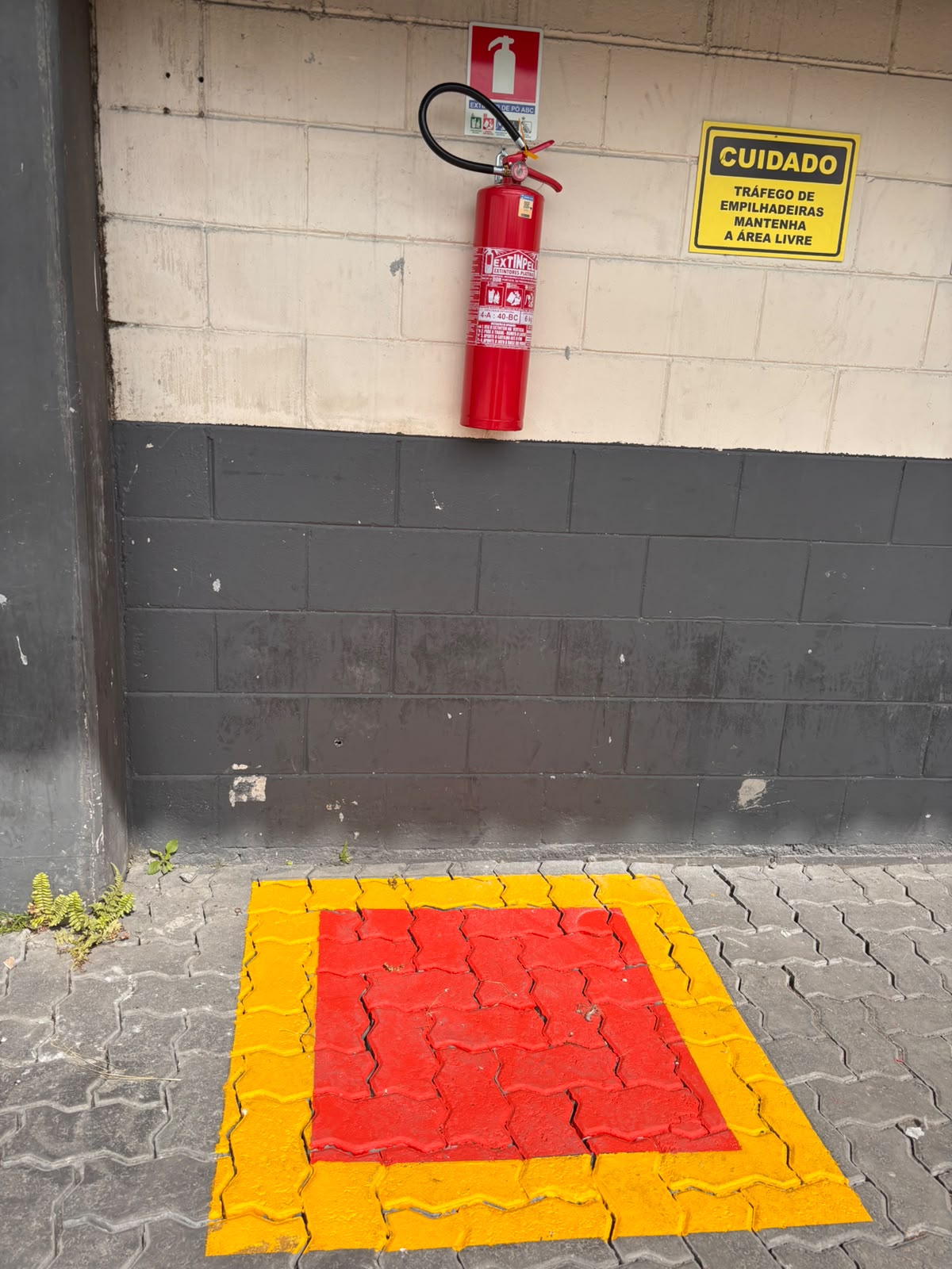 Extintor e sinalização de emergência em parede industrial